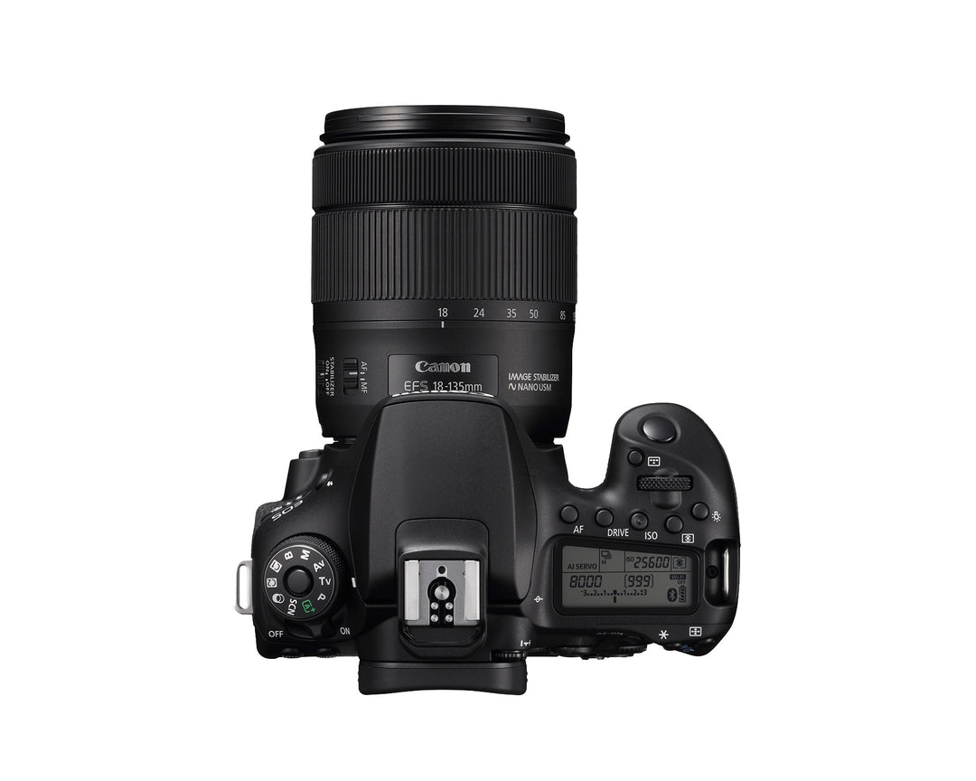 Top of the Canon EOS 90D showing the mode dial, top LCD panel, hot shoe and the 18-135mm lens zoomed out