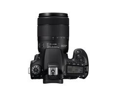Top of the Canon EOS 90D showing the mode dial, top LCD panel, hot shoe and the 18-135mm lens zoomed out