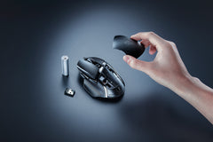Razer Basilisk V3 X HyperSpeed in Black with its top cover lifted off, next to the AA battery and the USB wireless dongle