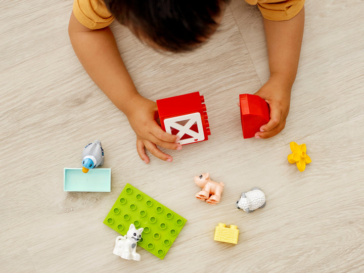 Toddler playing with the LEGO DUPLO Farm Animal Care set, overhead view