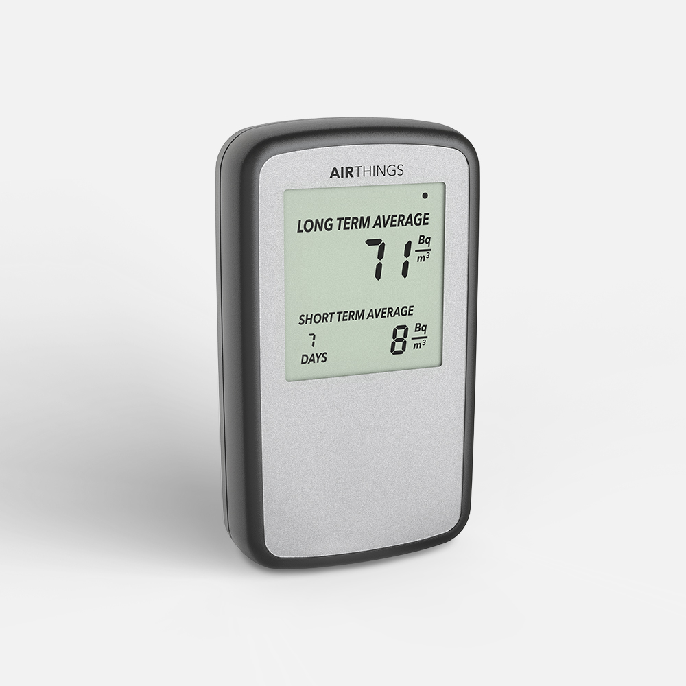 Airthings Corentium Home radon detector at a three-quarter angle, silver-grey face in a black frame