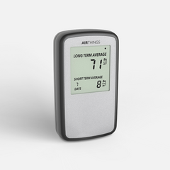 Airthings Corentium Home radon detector at a three-quarter angle, silver-grey face in a black frame