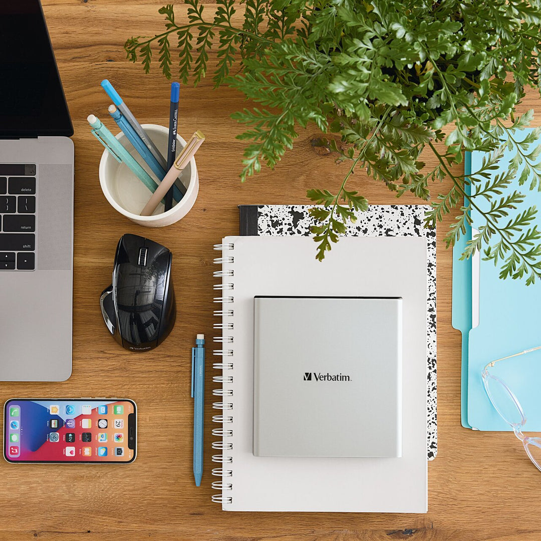 Top view of the Verbatim External All-in-One Optical Writer on a notebook next to a laptop and mouse