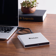 Verbatim External All-in-One Optical Writer connected to a laptop by its USB cable on a wooden desk