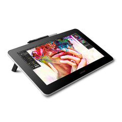 Wacom One 13.3 inch pen display at an angle on its fold-out legs, with the Wacom One Pen in its holder on the top edge