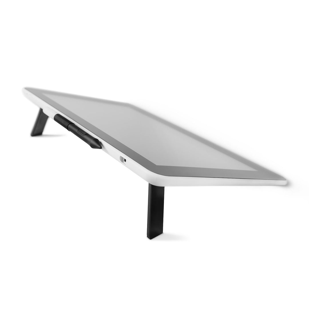 Wacom One pen display raised on its fold-out legs, showing the pen holder on the edge of the white back
