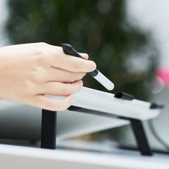 Hand lifting the Wacom One Pen from the pen holder on the top edge of the display